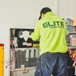Technik montuje domowy magazyn energii przy ścianie wewnątrz budynku