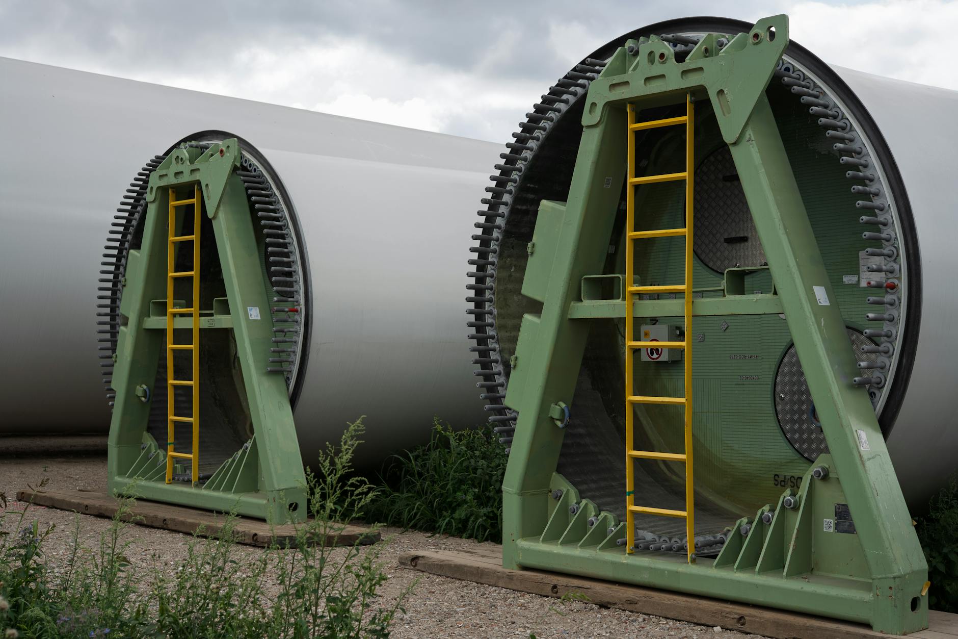 Łopaty turbin wiatrowych składowane na metalowych stojakach na zewnątrz